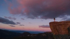 Image d'un homme sur une falaise au coucher du soleil