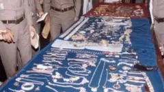 উদ্ধারকরা গহনা দেখাচ্ছে পুলিশ, পাশেই হাতকড়া পরা ক্রিয়াংক্রাই