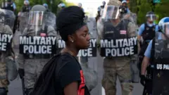 Black woman in front of police in riot gear