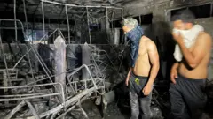 رجلان داخل أحد أجنحة المستشفى المتفحمة