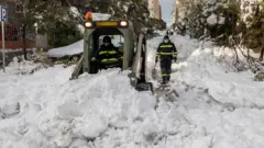 Municipal workers clear snow on a street Madrid on 10 January 2021