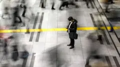 A man wearing a protective face mask stands at the Shinagawa station in Tokyo