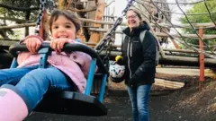Leonor en un parque infantil con su madre.