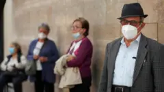People wearing protective face masks attend the rosary prayer on a street in Rome