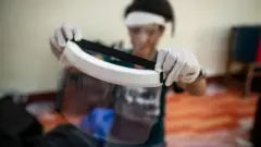 طالب طب يتفحص درع الوجه اليدوي قبل تسليمه للأطباء والممرضات في يانغون، ميانمار.