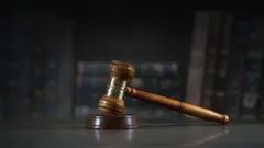 Martelo que representa a Justiça com livros ao fundo