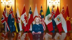 Liz Truss posing next to flags representing the nations in the trade deal