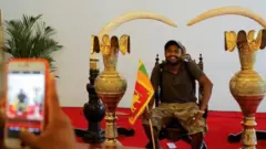 राष्ट्रपतिको आसनमा बसेर फोटो खिचाउँदै एक प्रदर्शनकारी