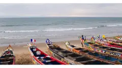 Plage avec une large vue sur l'océan Atlantique, avec des bateaux à l'eau au premier plan.