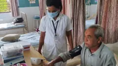 દર્દીને તપાસતાં નર્સ