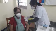 নর্থ বেঙ্গল মেডিকেল কলেজে একজন স্বাস্থ্যকর্মী টিকা নিচ্ছেন