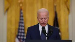 Biden em pé discursando em frente a microfone na Casa Branca