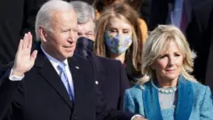 President Biden places his hand on a large Bible