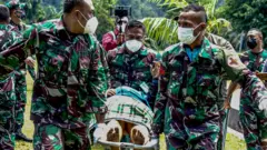 Prajurit TNI AD menggotong tenaga kesehatan (Nakes) korban penyerangan Kelompok Kriminal Bersenjata (KKB) usai dievakuasi menggunakan helikopter milik TNI AD di Lapangan Frans Kaisepo Makodam XVII Cenderawasih, Kota Jayapura, Papua, Jumat (17/09)