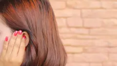 一名女人把手放在耳朵上