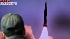 رجل يشاهد تقريرا تلفزيونيا يظهر بثا إخباريا لتجربة صاروخ كوري شمالي، في 19 أكتوبر/تشرين أول 2021