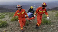 Rescuers carrying equipment as they search for runners who were competing in a 100-kilometre cross-country mountain race when extreme weather hit the area