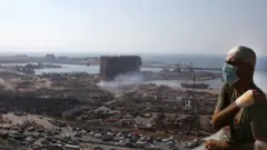 شخص مصاب بانفجار بيروت، يظهر خلفه مرفأ بيروت