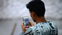 شاب هندي يتابع هاتفه الذكي