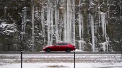 A rock wall covered with ice on Interstate 71 as snow begins to fall in Louisville, Kentucky, February 15, 2021