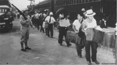 Japoneses vigilados por un militar