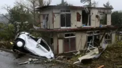 Un auto incrustado en una casa en Chiba, por el tifón.