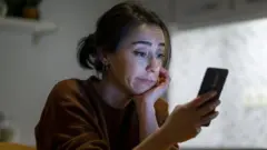 Mulher com cara de insatisfeita olhando para celular