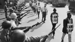 ১৯৬৮ তে সিভিল রাইটস মুভমেন্টের সময় একটি মিছিলে অস্ত্র তাক করে ন্যাশনাল গার্ডের সদস্যরা