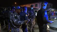 Police officers stand at a road block while they accompany Vincent Toh Bi