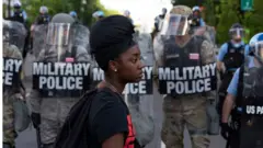 Black woman in front of police in riot gear