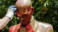 Volunteers of the association Retake clean a statue of famous Italian journalist Indro Montanelli, which stands in a garden of the same name, that was sprayed painted red and tagged with the words racist and rapist, in Milan, Italy, 14 June 2020. An anti-fascist group had called on Milan"s mayor to remove the statue because Montanelli bought and married a young Eritrean girl after volunteering for Fascist leader Benito Mussolini"s colonial invasion of Ethiopia in 1935.