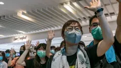 示威者在商場上舉起手，表達對五大訴求的堅持。