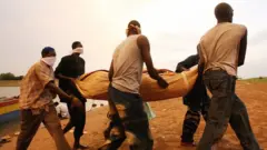 Some men wey carry wrapped body of one victim of one sinking boat for lake Volta, 11 April 2006 for Tapa Popoassy village.