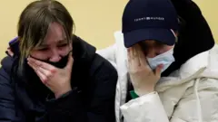 People from Ukraine react as they stay at a refugee shelter, after Russia launched a massive military operation against Ukraine, in Tiszabecs, Hungary February 28, 2022