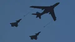 Indege y'intambara yo mu bwoko bwa Xian H-6U iha ibitoro (hagati) indi ndege mu kirere, iguruka hamwe n'izindi ebyiri z'intambara zo mu bwoko bwa Chengdu J-10