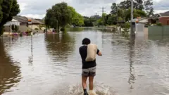 A local resident carries a sandbag through floodwaters as the state of Victoria faces an ongoing flood crisis, in Shepparton, Australia, October 16, 2022.