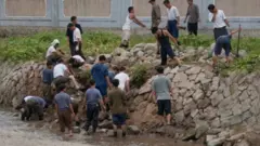 지난 2011년 폭우 피해 당시 황해북도 개성에서 강둑을 보수하는 북한 남성들