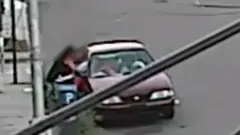 Mulher puxa menino por janela de carro estacionado