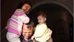 कंधों पर बच्चों को बिठाए पिता