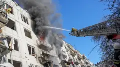 Ukrainian firefighters try to extinguish a fire after an airstrike hit an apartment complex in Chuhuiv, Kharkiv Oblast, Ukraine on 24 February 2022