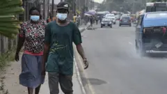 Des gens marchent le long d'une route principale en portant des masques à Yaba à Lagos, le 28 février 2020.