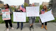 Protesters hold signs encouraging people to demand that businesses be allowed to open up in Kansas City, Missouri.