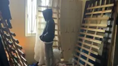 شاب لا يظهر وجهه ينظر من النافذة.