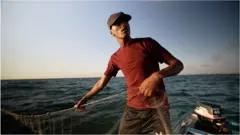 Pescador em cima de barco segura rede