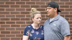Samantha and Dave Stewart against a brick wall