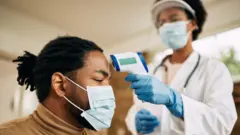 Un médecin prend la température d'un patient.