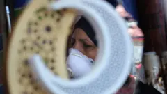 Haweeney Ciraaq ku nool oo xiran maaskiga wejiga oo u adeegsaneysa bisha ramdan