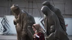 مجسمه‌ نمادین زائران در نزدیکی محل دفن امام هشتم شیعیان در مشهد