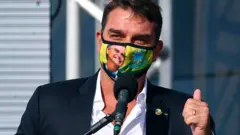 Flávio Bolsonaro com máscara com foto de Jair Bolsonaro