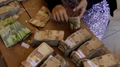 Warga menghitung uang lusuh yang akan ditukarkan dengan uang baru,saat digelar Ekspedisi Kas Keliling Pulau Terluar, Terdepan dan Tertinggal (3T), di desa Tamher Timur, Pulau Kesui, Maluku, Jumat (2/11/2018).